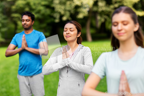 Image of group of people doing yoga at summer park