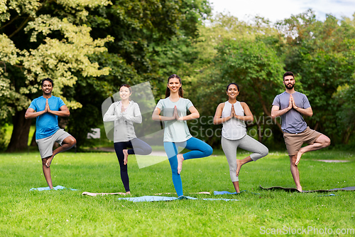 Image of group of people doing yoga at summer park