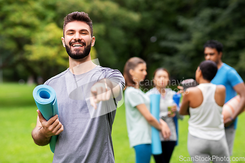 Image of happy man with yoga mat pointing finger to camera