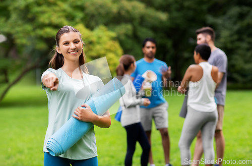 Image of woman with yoga mat pointing finger to camera