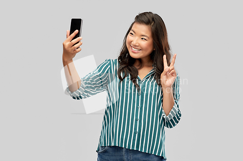 Image of smiling asian woman taking selfie by smartphone