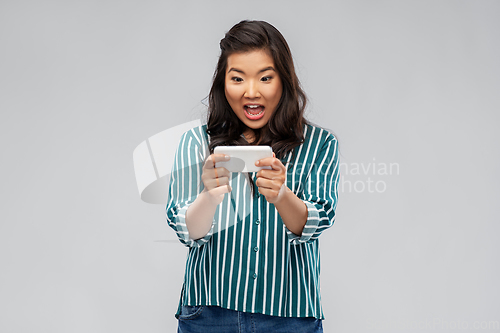 Image of surprised asian woman using smartphone