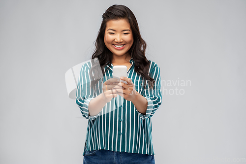 Image of happy asian woman using smartphone