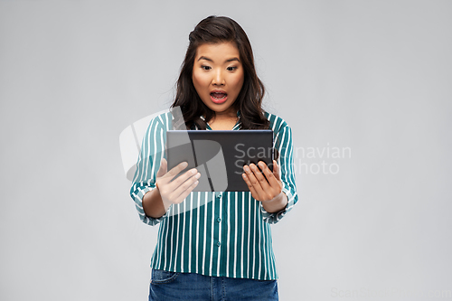 Image of surprised asian woman using tablet computer