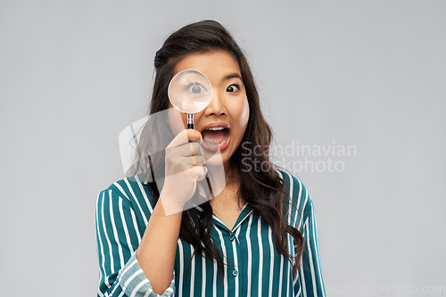 Image of asian woman looking through magnifying glass