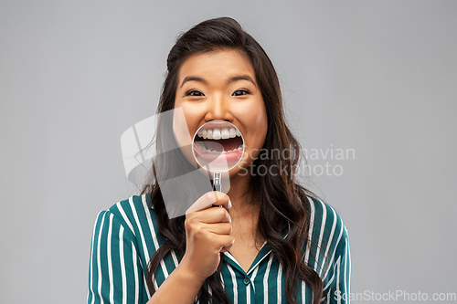 Image of asian woman shows teeth through magnifying glass