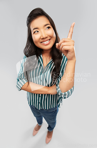 Image of happy smiling asian woman pointing finger up