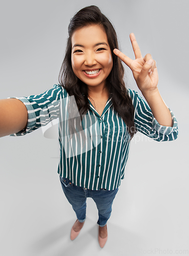 Image of happy asian woman taking selfie and showing peace