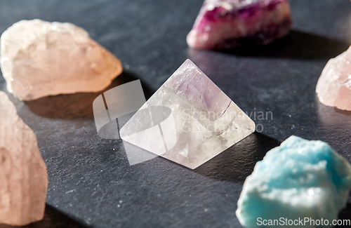 Image of quartz crystal pyramid and gem stones on slate