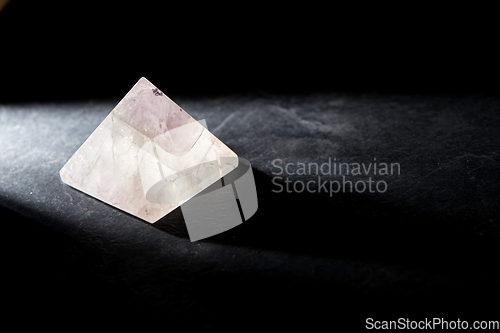 Image of quartz crystal pyramid on slate stone in darkness