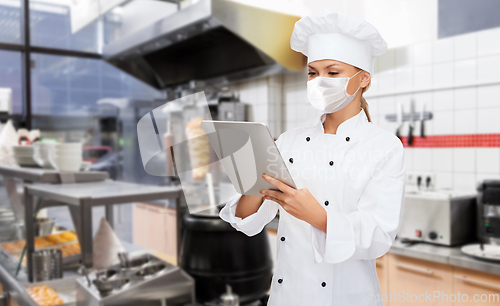 Image of female chef in mask with tablet pc at kitchen