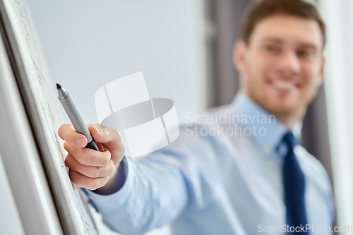 Image of businessman with marker at flip chart at office