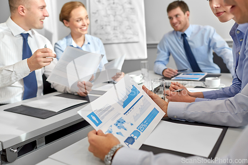 Image of happy business team with papers meeting at office