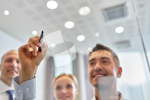 Image of man with marker writing on glass wall at office