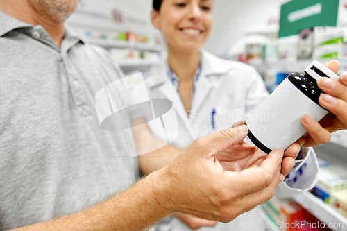 Image of pharmacist and old man with medicine at pharmacy