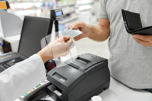 Image of close up of hand giving bank card to pharmacist