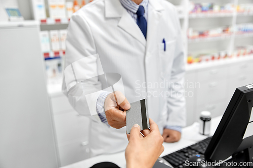 Image of close up of hand giving bank card to pharmacist