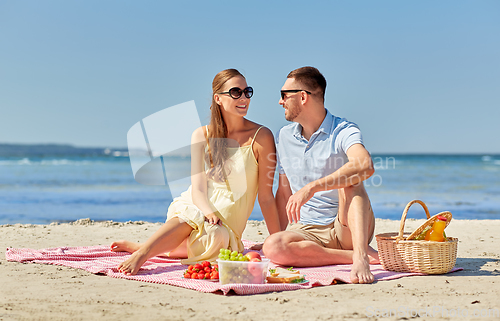 Image of happy couple having picnic on summer beach