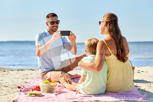 Image of family with smartphone photographing on beach