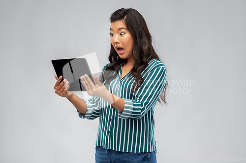 Image of shocked asian woman using tablet computer