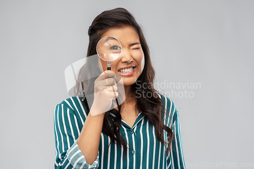 Image of asian woman looking through magnifying glass