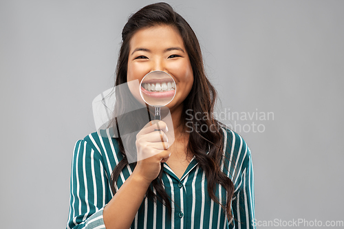 Image of asian woman shows teeth through magnifying glass