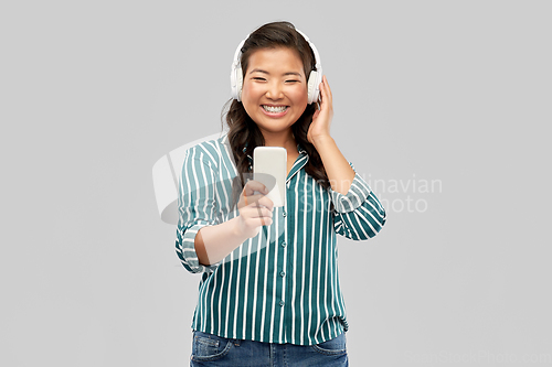 Image of happy asian woman in headphones listening to music