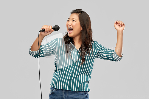 Image of happy asian woman with microphone singing