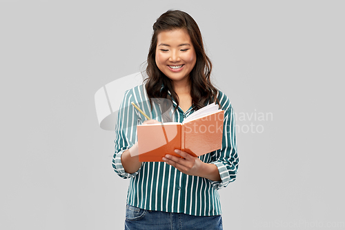 Image of happy asian student woman with diary and pencil