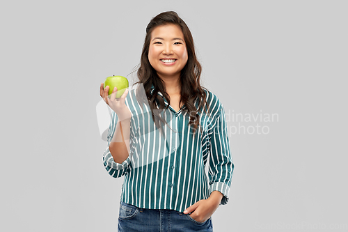 Image of happy smiling asian woman holding green apple