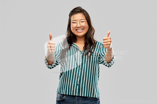 Image of happy asian woman in glasses showing thumbs up
