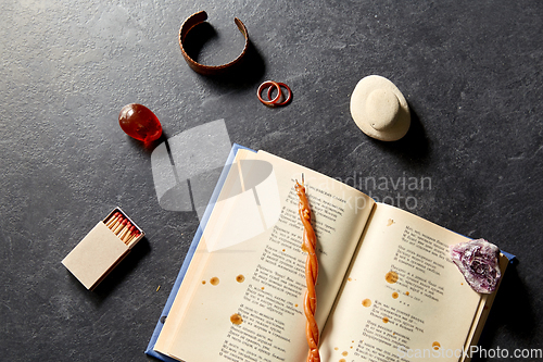 Image of magic book, wax candle, matches and gem stones