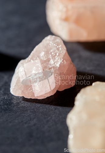 Image of raw rose quartz crystals on black slate background