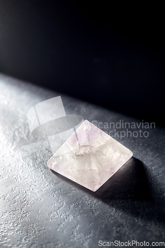 Image of quartz crystal pyramid on slate stone in darkness