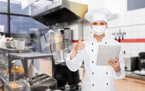 Image of female chef in mask with tablet pc at kitchen