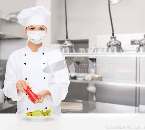 Image of female chef in mask cutting vegetables at kitchen