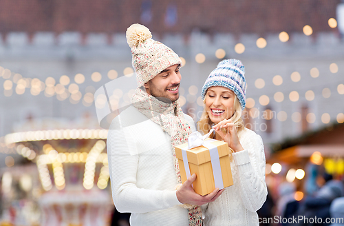 Image of smiling couple in winter clothes with gift box