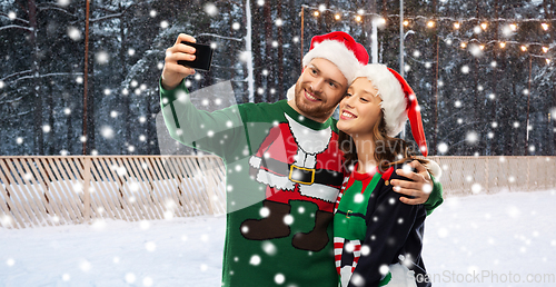 Image of happy couple in christmas sweaters taking selfie