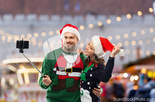 Image of happy couple in christmas sweaters taking selfie