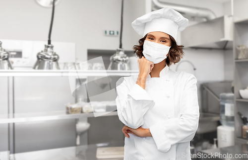 Image of female chef in mask at restaurant kitchen