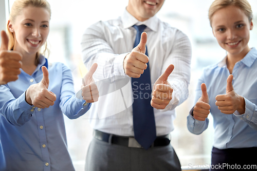 Image of happy business team showing thumbs up at office