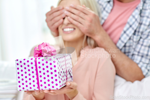 Image of happy couple with gift box at home