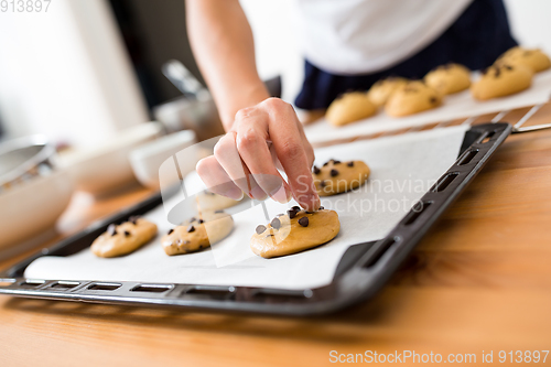 Image of Woman adding chocolate bean on cookies