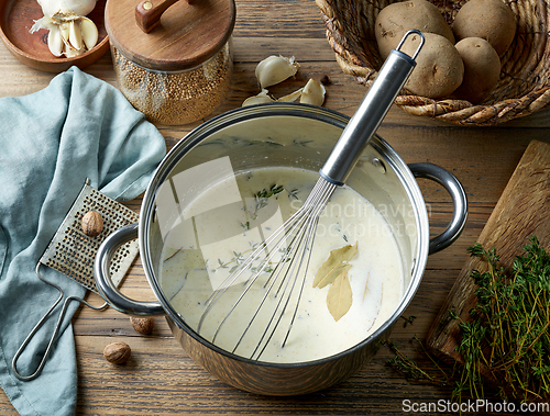 Image of pot with hot mixed milk cream and herbs 