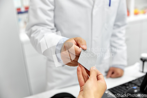 Image of close up of hand giving bank card to pharmacist