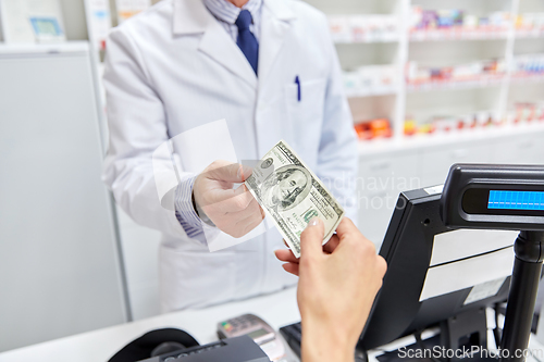 Image of pharmacist taking money from customer at pharmacy