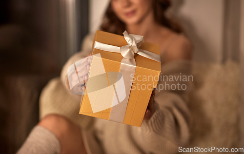 Image of woman with christmas gift at home at night