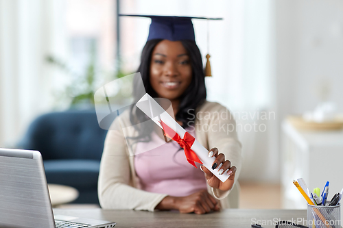 Image of graduate student with laptop and diploma at home