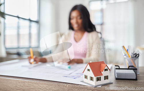 Image of house model and female architect working at office