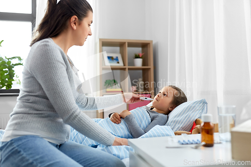 Image of mother and sick daughter measuring temperature